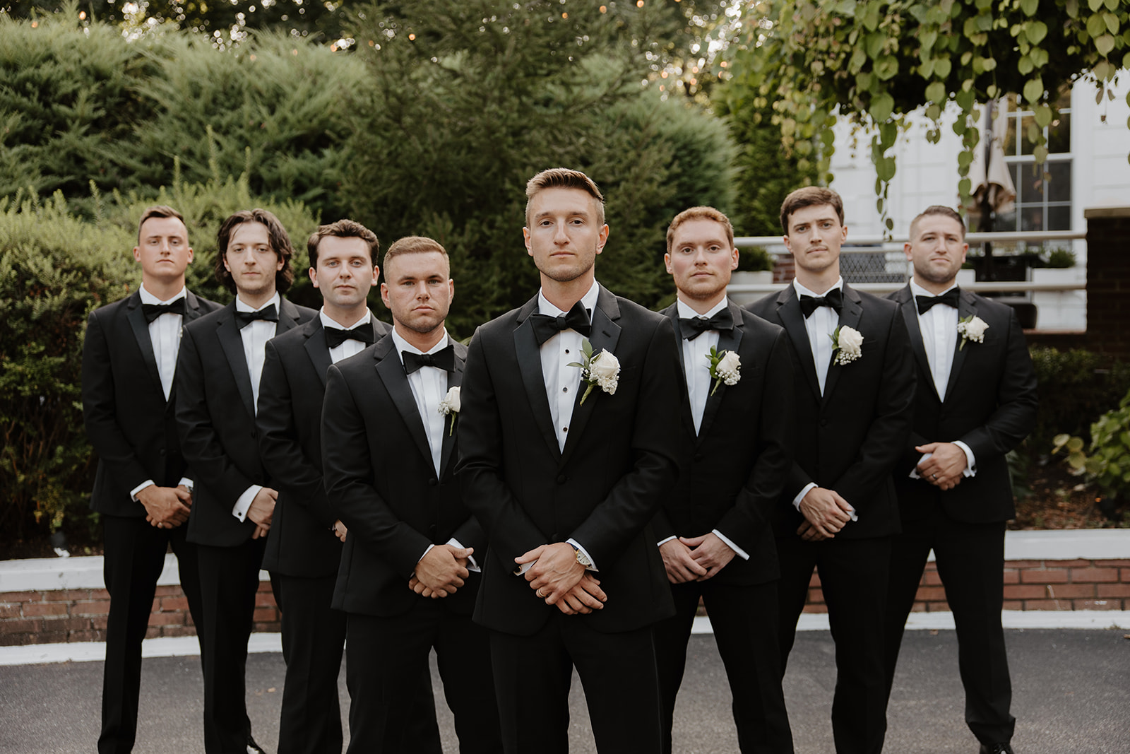 Groom standing confidently in front of his groomsmen, all dressed in matching black tuxedos.